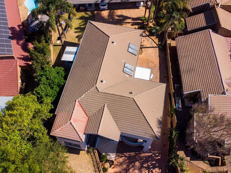 Aerial view of the property showcasing the tiled roof structure, integrated solar panels, skylights, and surrounding paved driveway area.