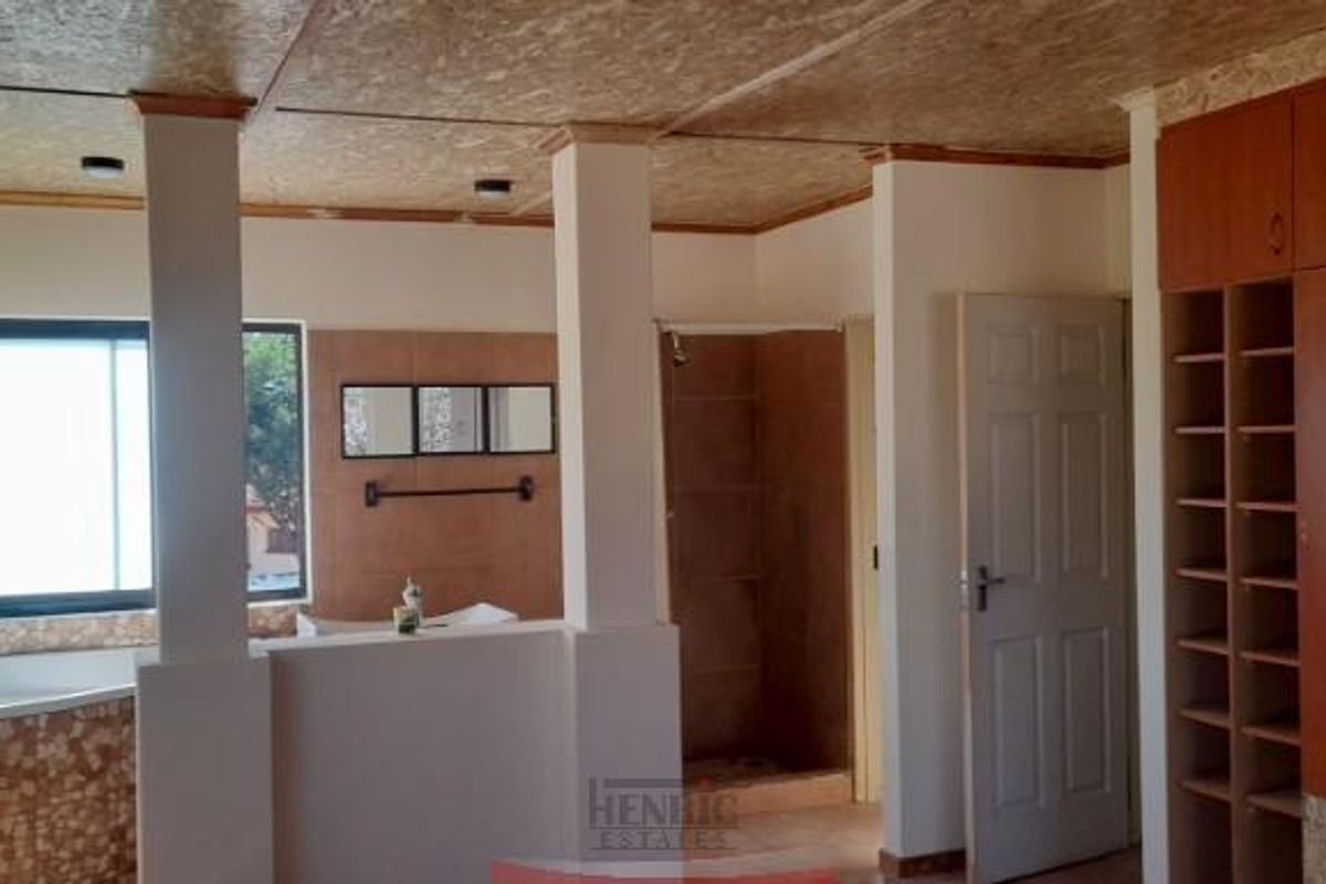 A spacious bathroom featuring a corner bathtub, walk-in shower, and extensive built-in wooden cabinetry with open shelving and storage compartments.