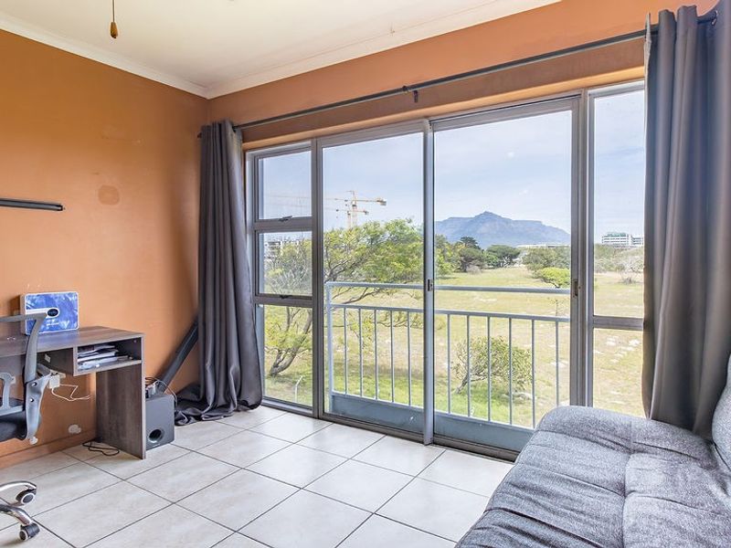 A bedroom featuring tiled flooring and large sliding glass doors that open onto a balcony with scenic mountain views.