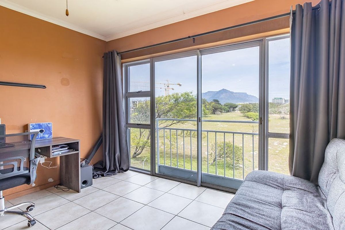 A bedroom featuring tiled flooring and large sliding glass doors that open onto a balcony with scenic mountain views.