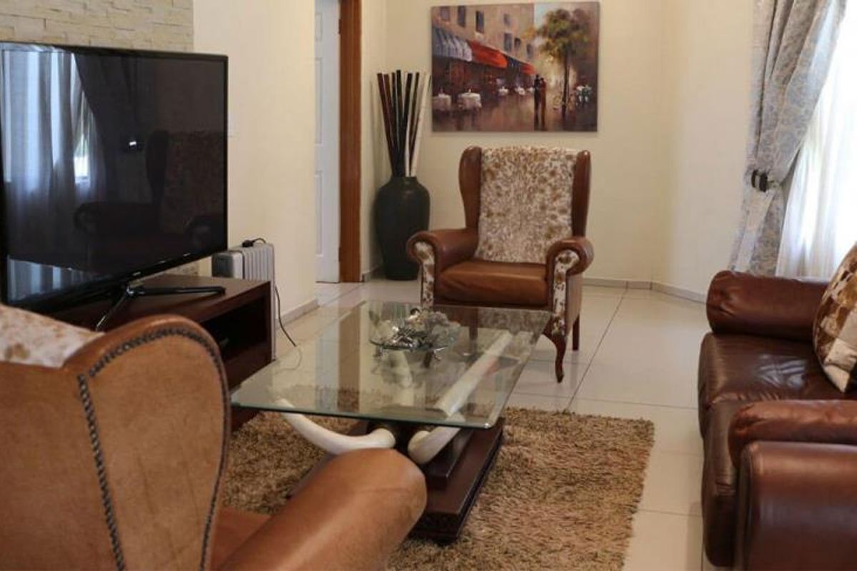A comfortable living room featuring a textured stone feature wall and neutral tiled flooring, providing a warm and inviting space.