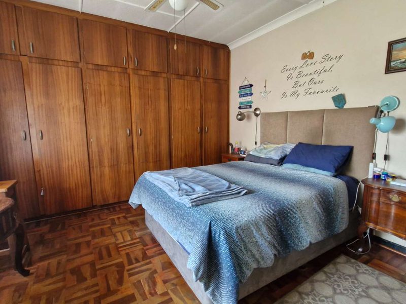 A bedroom featuring classic parquet flooring and extensive floor-to-ceiling built-in wooden cabinetry, providing ample storage space.