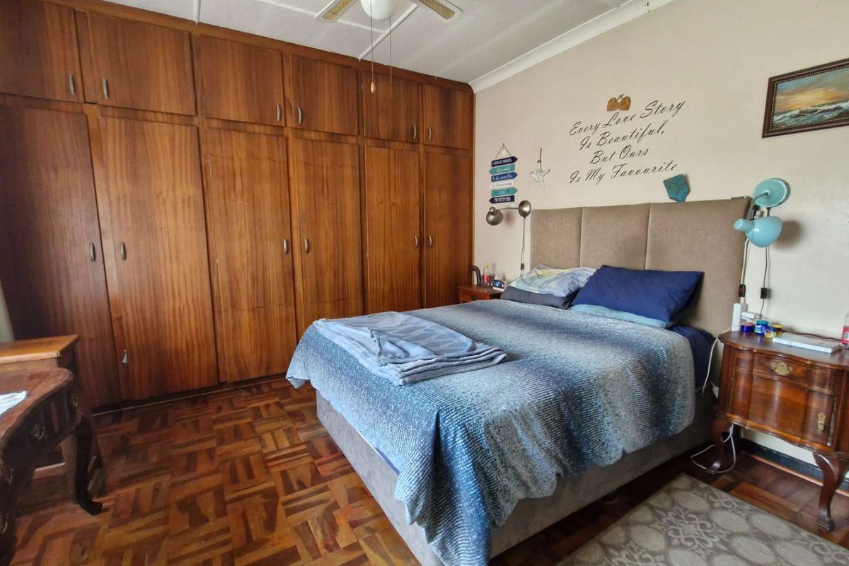 A bedroom featuring classic parquet flooring and extensive floor-to-ceiling built-in wooden cabinetry, providing ample storage space.