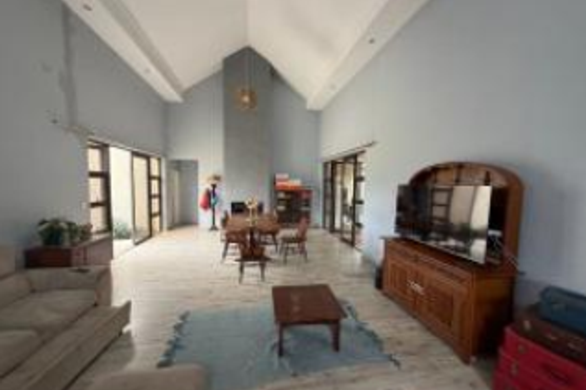 Spacious open-plan living and dining area featuring a high vaulted ceiling, central fireplace, and large sliding glass doors leading to the exterior.