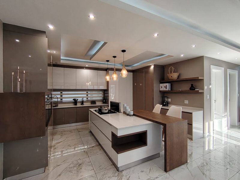 Modern, high-end kitchen featuring a central island with integrated hob, sleek cabinetry, marble-look flooring, and sophisticated recessed ceiling lighting.
