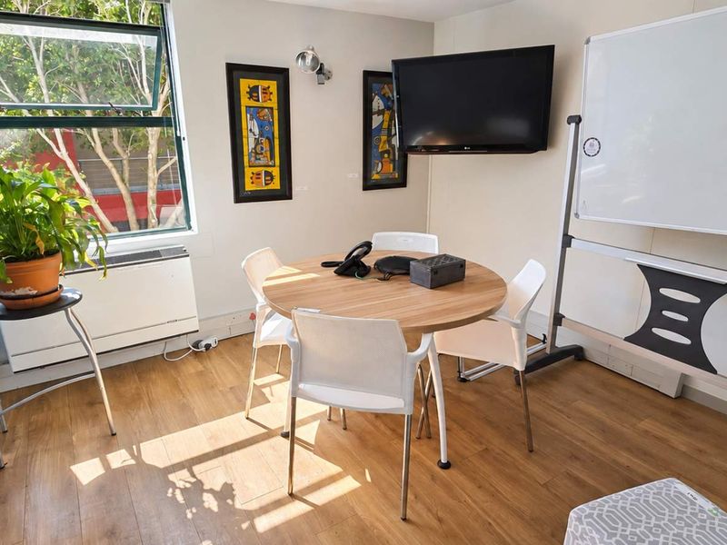 A functional office space featuring laminate flooring, a wall-mounted heater, and a large window providing natural light.