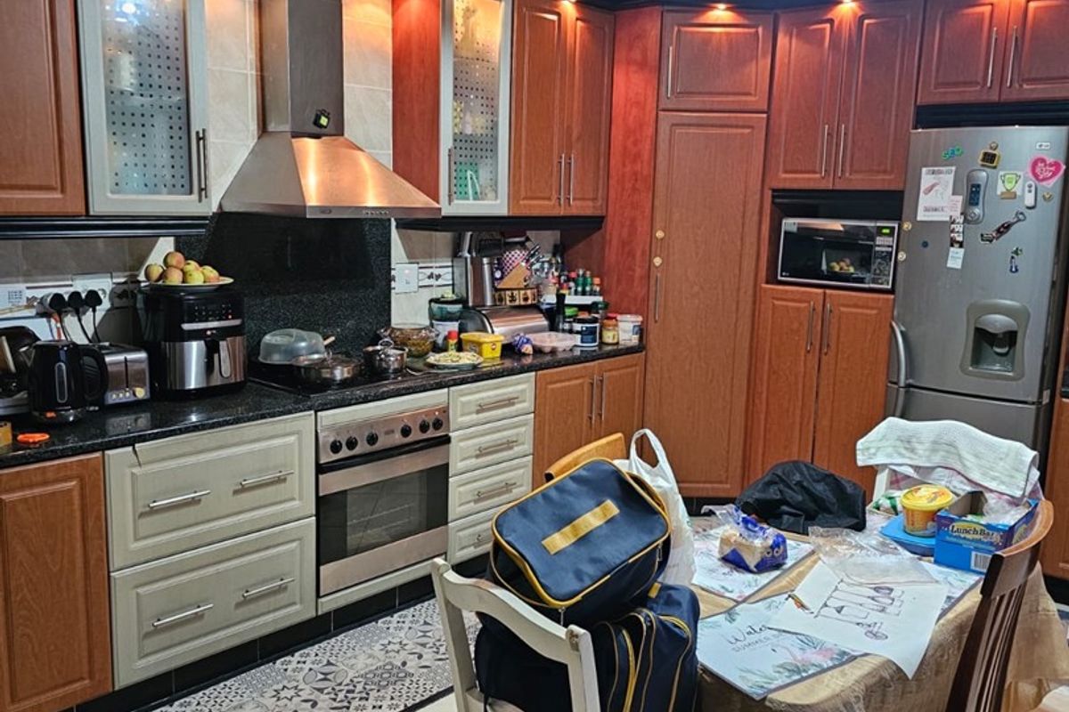 A functional kitchen featuring wooden cabinetry, granite countertops, built-in appliances, and tiled flooring, offering a practical layout for daily cooking and dining.