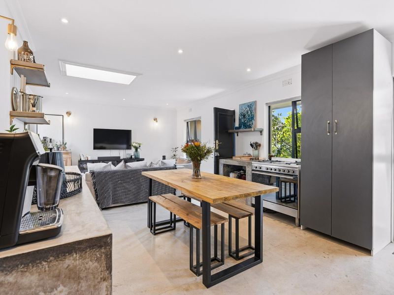 Modern open-plan living area featuring a concrete kitchen island, gas stove, skylight, and polished concrete floors, creating a bright and functional space.