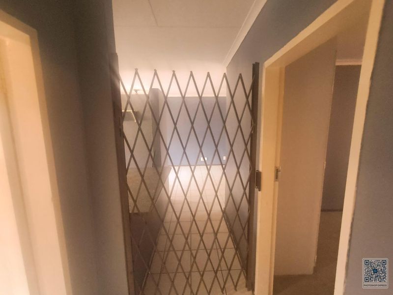 A hallway area featuring tiled flooring and a metal security gate, providing access to adjacent rooms within the townhouse.