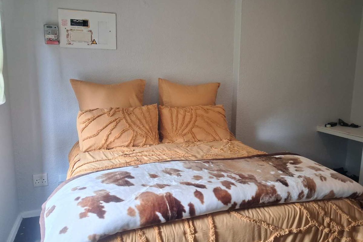A bedroom featuring a wall-mounted electrical distribution board and a small built-in shelf, providing basic utility and storage space.