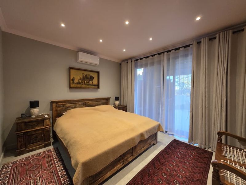 A well-maintained bedroom featuring recessed ceiling lighting, a wall-mounted air conditioning unit, and large sliding glass doors leading to an outdoor area.