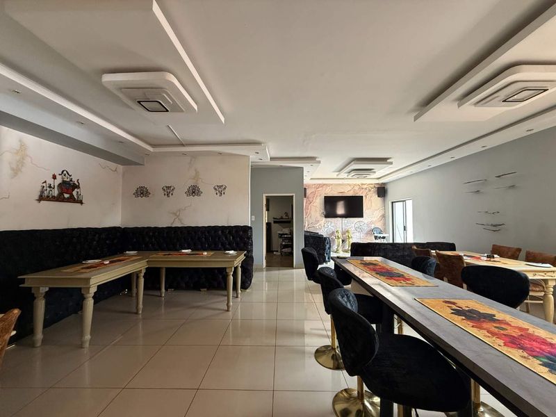 Spacious open-plan retail or dining area featuring tiled flooring, recessed ceiling details, and decorative wall finishes.