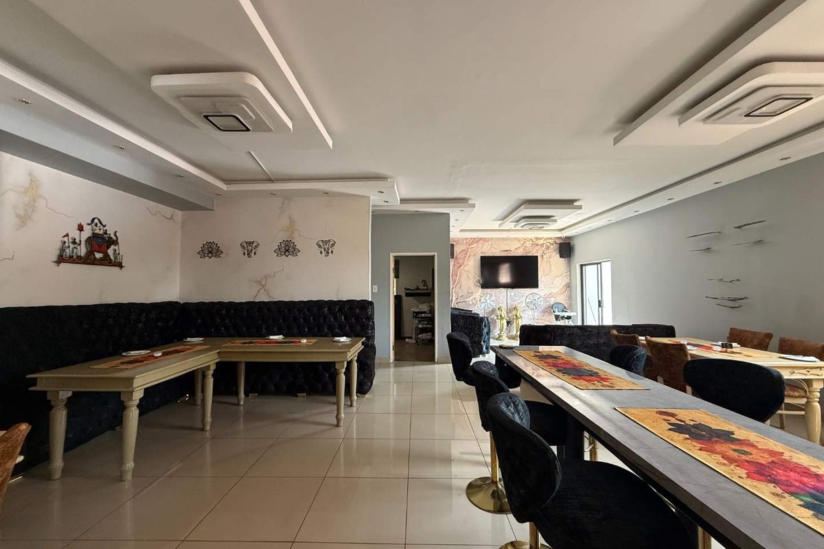 Spacious open-plan retail or dining area featuring tiled flooring, recessed ceiling details, and decorative wall finishes.