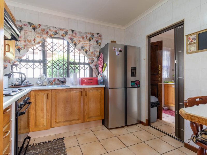 A functional kitchen featuring wooden cabinetry, tiled surfaces, and a built-in oven, with a folding door leading to an adjacent utility area.