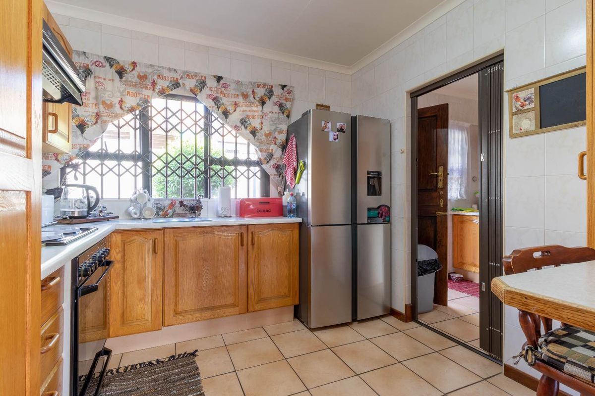A functional kitchen featuring wooden cabinetry, tiled surfaces, and a built-in oven, with a folding door leading to an adjacent utility area.