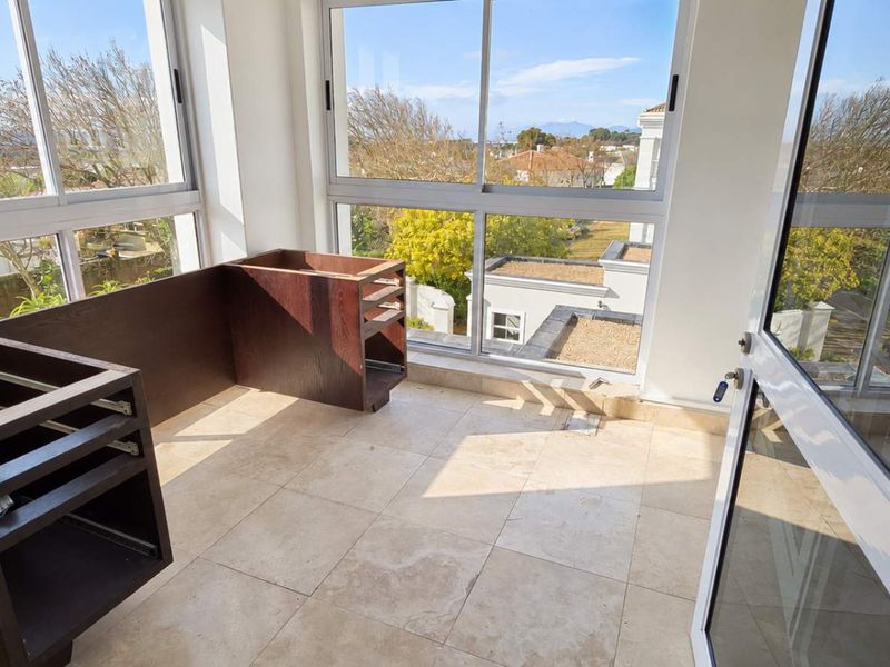 A bright office space featuring large windows with scenic views, tiled flooring, and unfinished built-in cabinetry ready for customization.