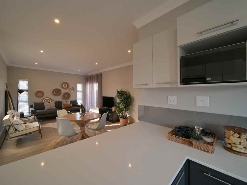 Modern open-plan living area featuring a sleek kitchen with quartz countertops, built-in microwave, and seamless flow into the dining and lounge space.