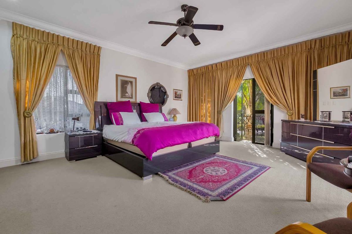 Spacious bedroom featuring neutral carpeting, crown molding, a ceiling fan, and direct access to an outdoor balcony through glass doors.