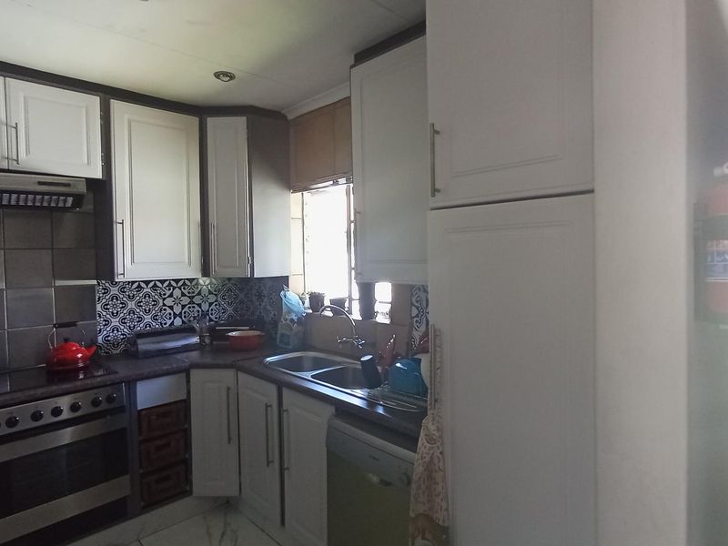 A functional kitchen featuring white cabinetry, a tiled backsplash, built-in oven and hob, and a double bowl sink.