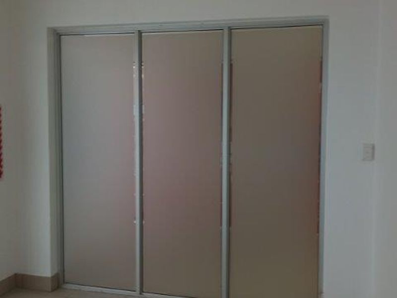 A clean, minimalist office space featuring neutral walls, sliding partition doors, and a wall-mounted fire extinguisher.