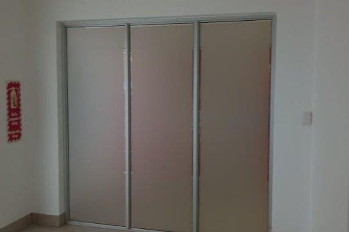 A clean, minimalist office space featuring neutral walls, sliding partition doors, and a wall-mounted fire extinguisher.