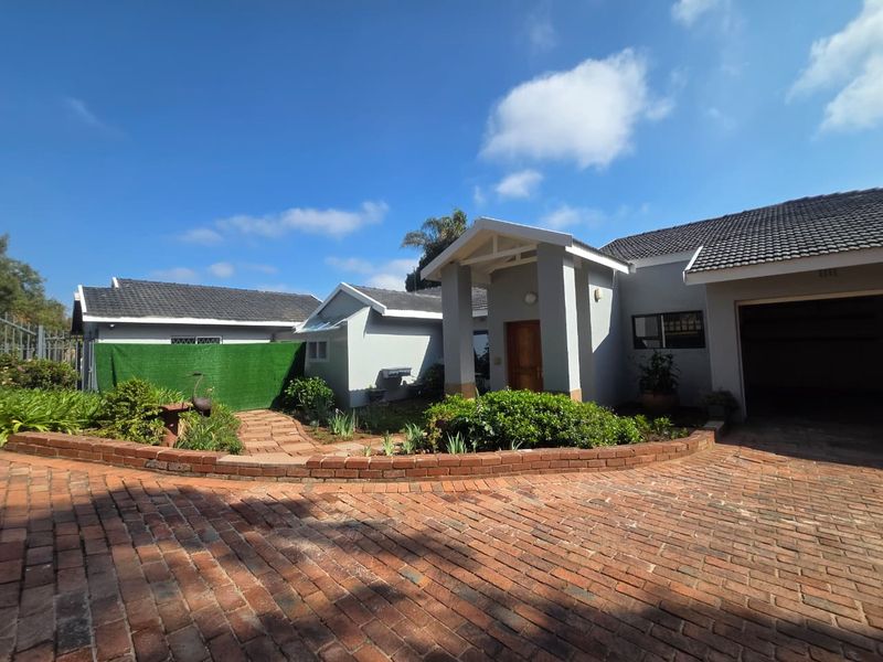 Front view of the house featuring a brick driveway, a low brick retaining wall, and a covered entrance with a tiled roof.