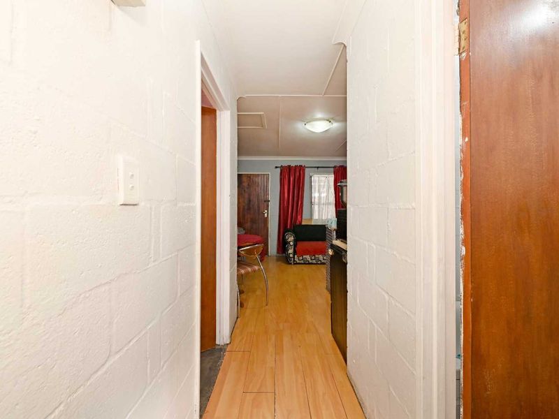 A narrow hallway featuring laminate flooring and painted blockwork walls, providing access to adjacent rooms within the property.
