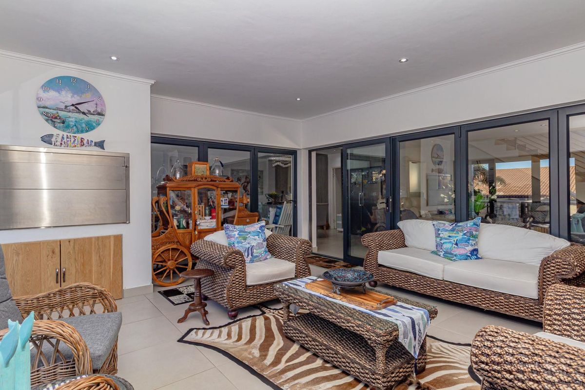A spacious indoor entertainment area featuring large sliding glass doors, recessed ceiling lighting, and a built-in stainless steel braai unit.