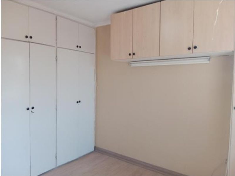 A bedroom featuring extensive built-in white cupboards and additional overhead storage cabinets, finished with laminate flooring.