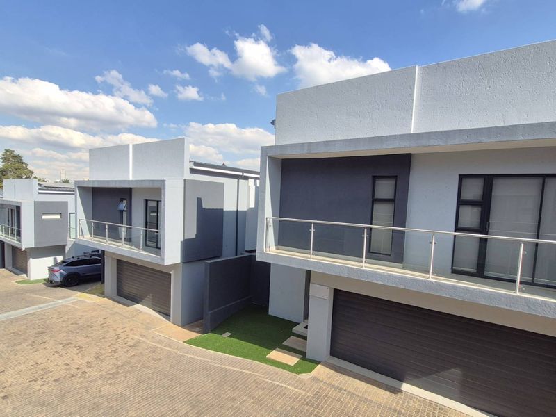 Modern cluster development featuring contemporary architectural design, paved driveways, automated garages, and upper-level balconies with glass balustrades.