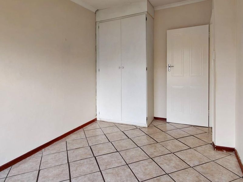 An empty bedroom featuring tiled flooring and a built-in wardrobe, providing a neutral canvas for personalization.
