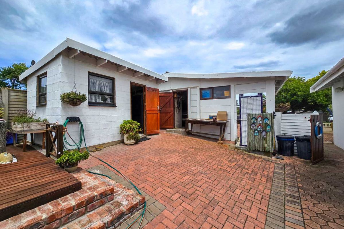 A rear courtyard featuring brick paving, a raised wooden deck, and access to the main dwelling structure.