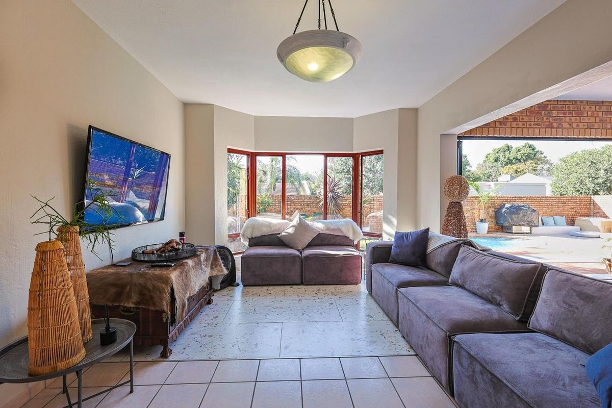 Spacious living room featuring large bay windows, terrazzo flooring, and seamless access to the outdoor patio and pool area.