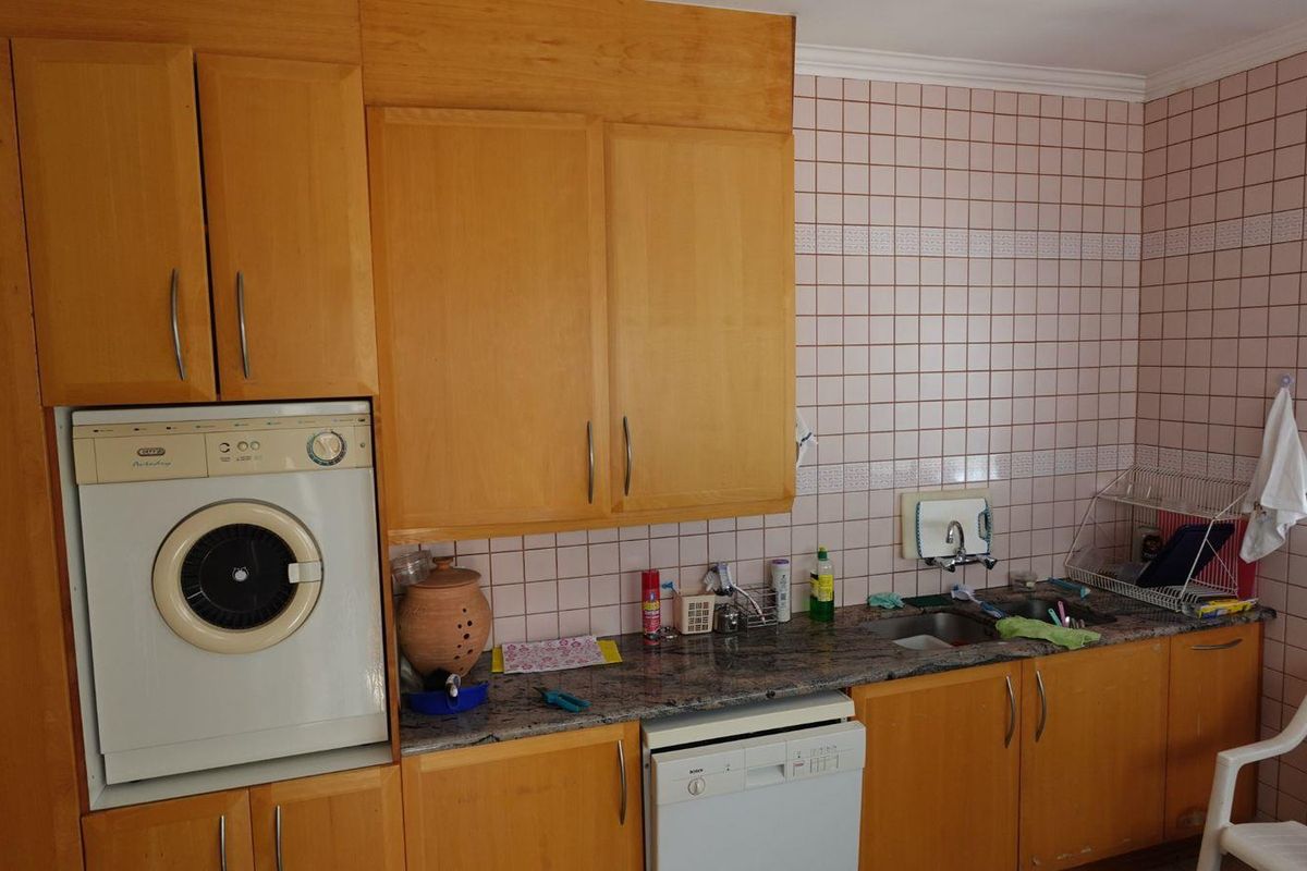 A functional kitchen featuring wooden cabinetry, granite countertops, a built-in oven, and tiled wall finishes.