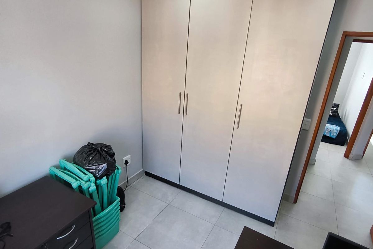 A bedroom featuring built-in cupboards with light-toned doors and tiled flooring, offering a clean and functional space.