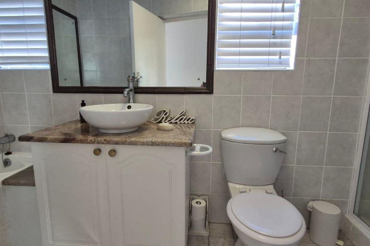 A functional bathroom featuring a vanity with a vessel sink, a separate bathtub, a shower enclosure, and a toilet with tiled walls.
