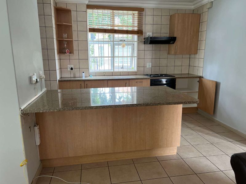 A functional kitchen featuring granite countertops, built-in oven, hob, extractor fan, and tiled finishes, offering a practical layout for daily meal preparation.