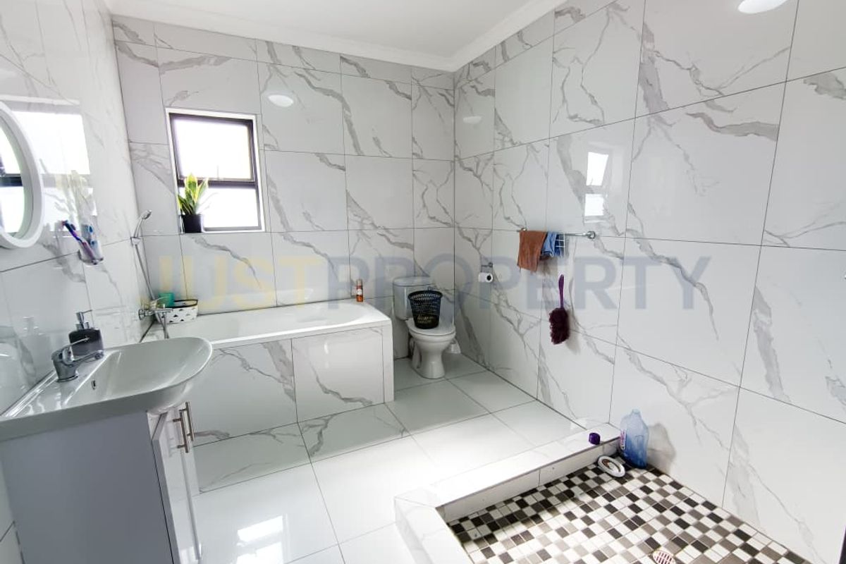 Modern bathroom featuring marble-look wall tiles, a built-in bathtub, a separate walk-in shower with mosaic tiling, and a vanity basin.