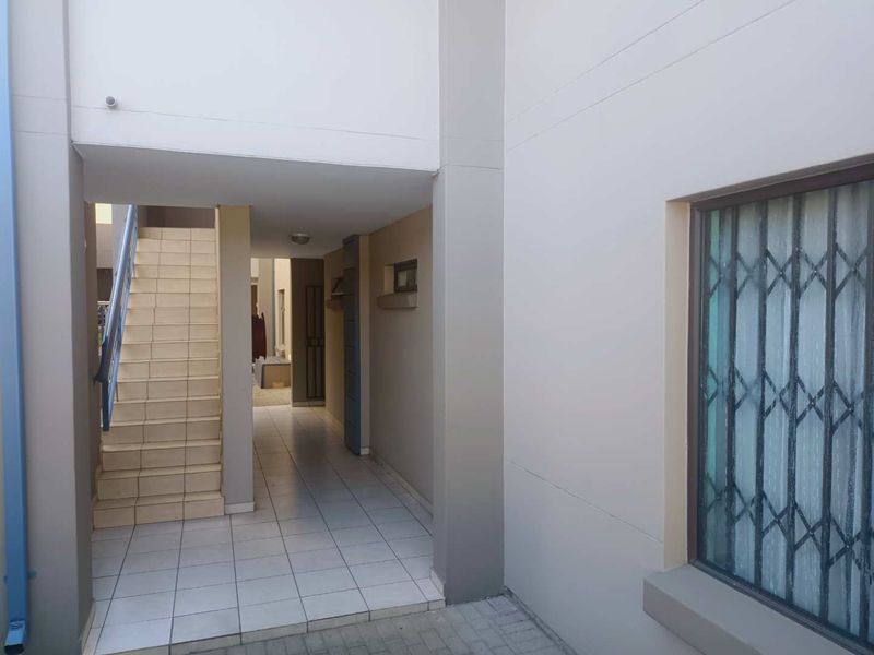 A clean exterior walkway and staircase area featuring tiled flooring and a secure metal gate, providing access to the apartment complex.