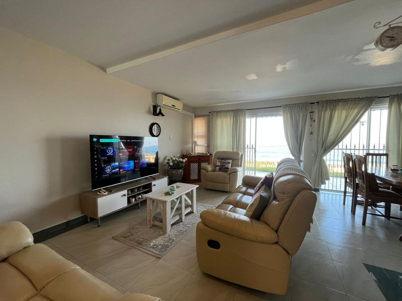 Open-plan living area featuring tiled floors, air conditioning, and direct access to a balcony with ocean views.