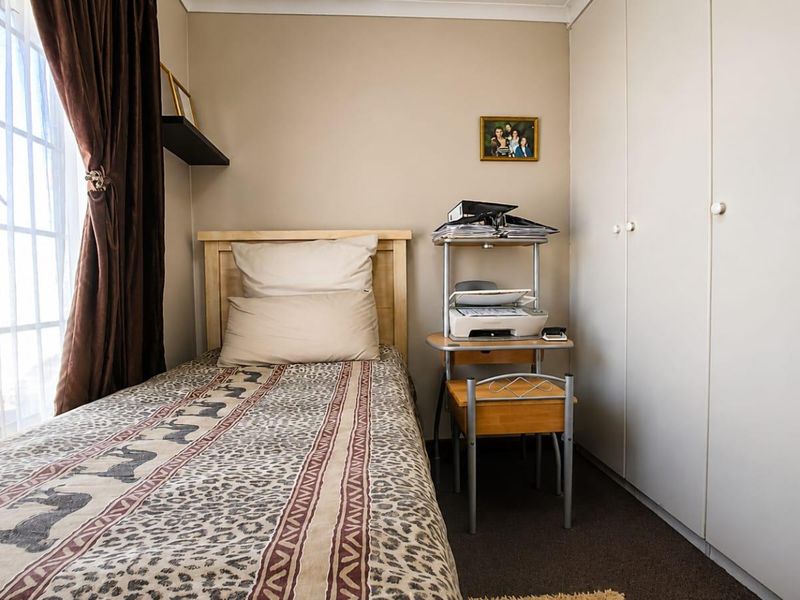 A functional bedroom featuring built-in cupboards and carpeted flooring, offering a practical space with natural light from the window.