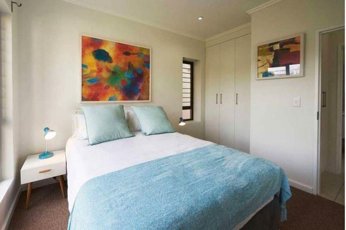 A well-maintained bedroom featuring built-in cupboards, recessed lighting, and neutral finishes, providing a comfortable and functional living space.