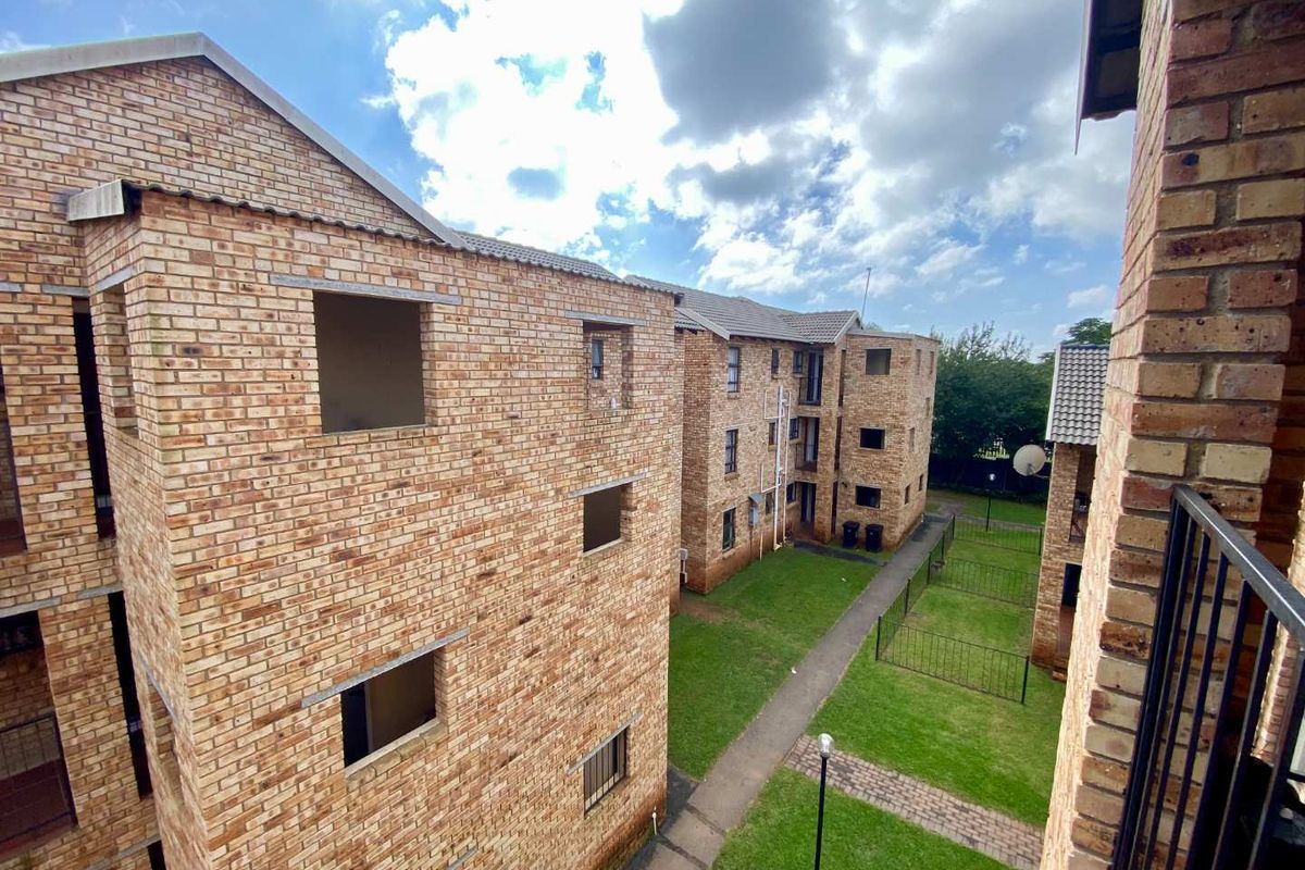 Exterior view of a multi-story apartment complex featuring face-brick facades, paved walkways, and communal green spaces between the residential blocks.
