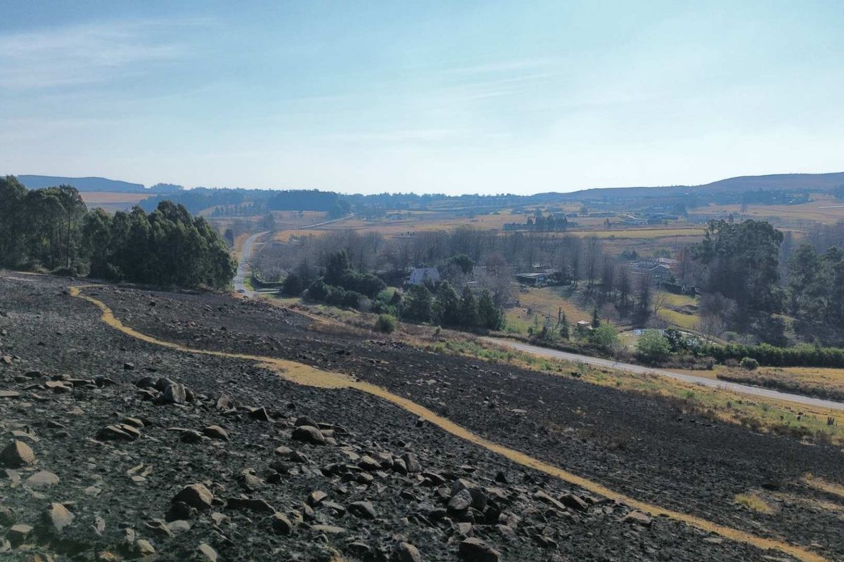 A wide-angle view of the surrounding rural landscape, featuring rolling hills, open fields, and a distant road winding through the countryside.