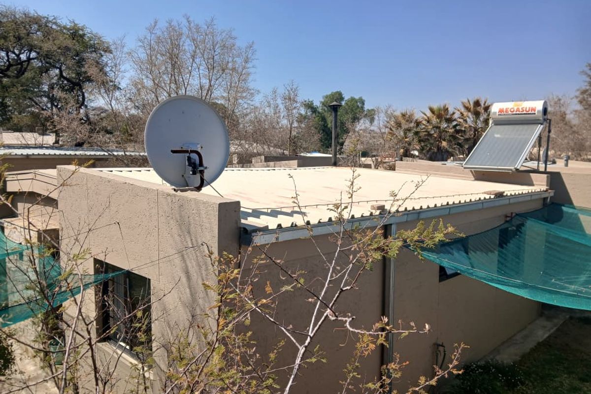 Rear exterior view of the townhouse featuring a corrugated metal roof, installed solar water heating system, and satellite dish.