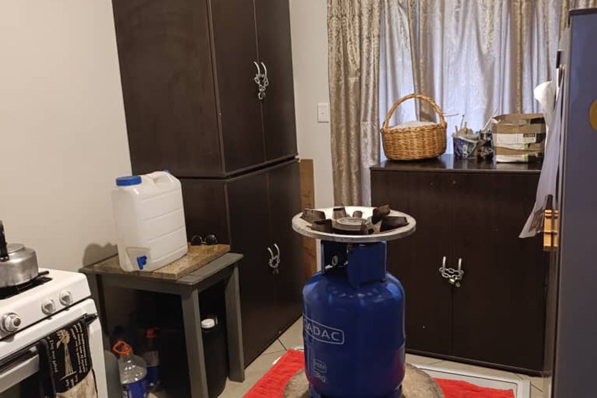 A functional kitchen area featuring tiled flooring, a built-in oven, and ample space for food preparation and storage.
