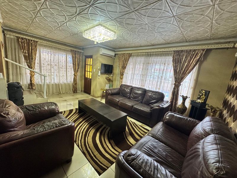 Spacious living room featuring tiled flooring, a decorative coffered ceiling, and a wall-mounted air conditioning unit.