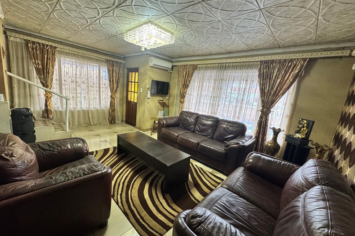 Spacious living room featuring tiled flooring, a decorative coffered ceiling, and a wall-mounted air conditioning unit.