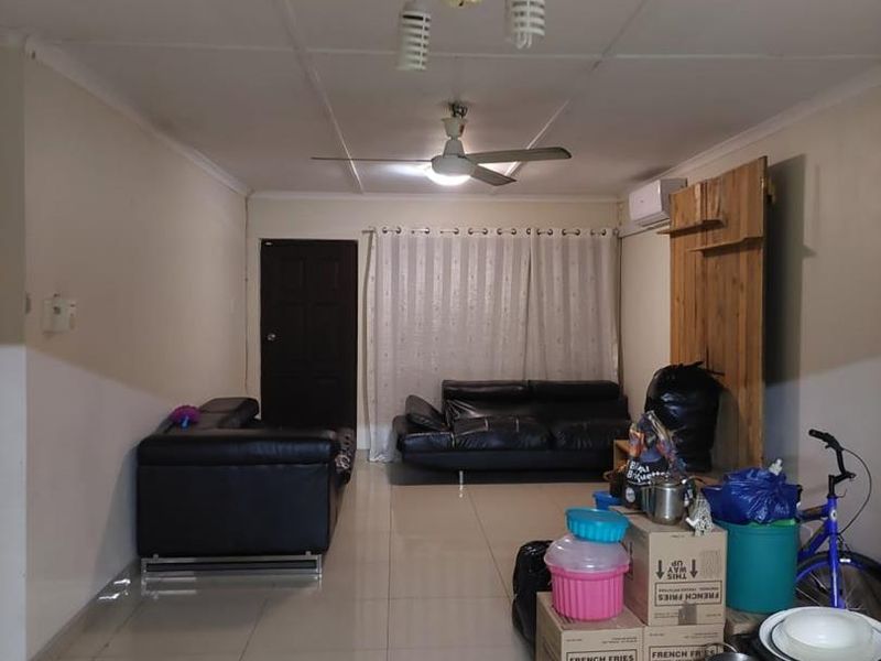 A living room featuring tiled flooring, a ceiling fan, and an air conditioning unit, currently used for storage.