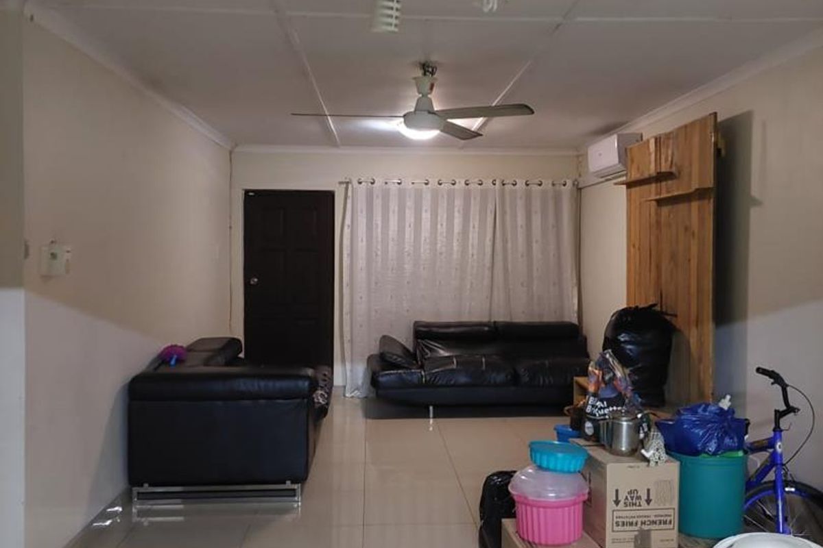 A living room featuring tiled flooring, a ceiling fan, and an air conditioning unit, currently used for storage.
